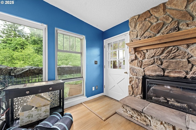 404 Chinook Ave, Astoria, OR 97103 - living room with lofted ceiling, a textured ceiling, wood finished floors, a fireplace, and baseboards