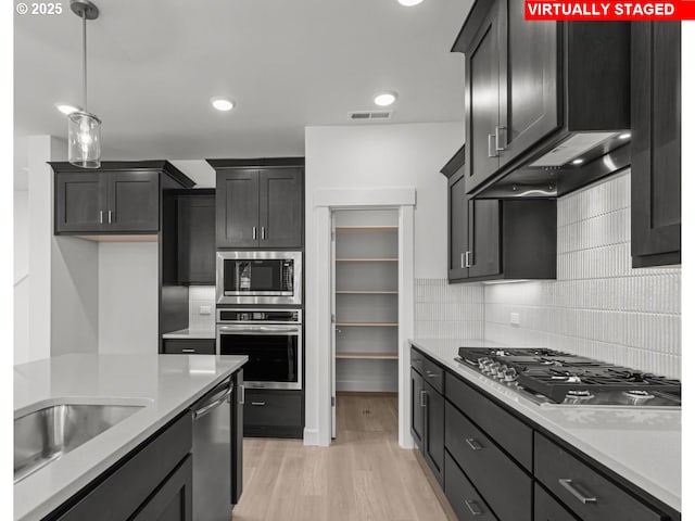 3430 SE 83rd Ave, Hillsboro, OR 97123 - kitchen with stainless steel appliances, light countertops, backsplash, light wood-type flooring, and pendant lighting