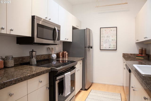 kitchen featuring tile counters, light wood-style flooring, stainless steel appliances, white cabinetry, and a sink