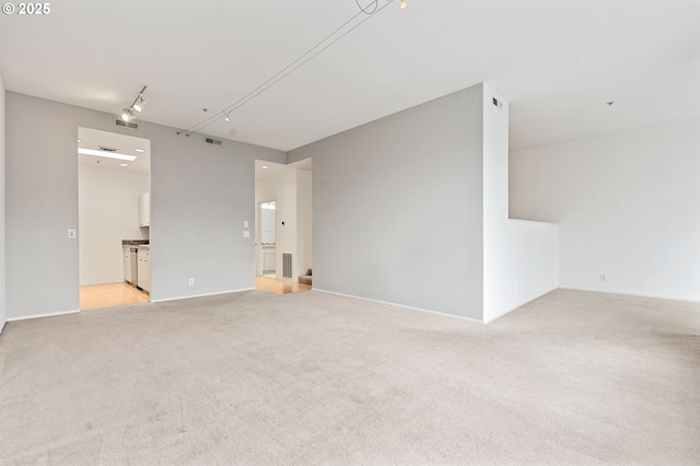 unfurnished room with light carpet, track lighting, and visible vents