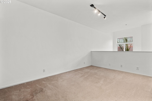 spare room with rail lighting, baseboards, and carpet floors