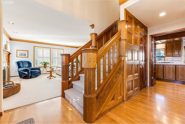 stairs featuring hardwood / wood-style flooring, ornamental molding, and a healthy amount of sunlight