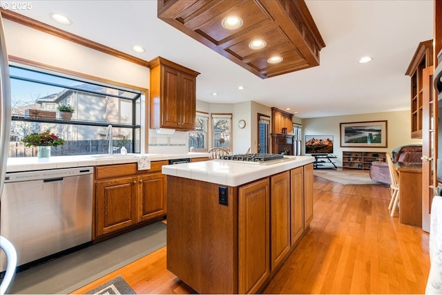 kitchen with sink, stainless steel appliances, a center island, tile counters, and light hardwood / wood-style floors