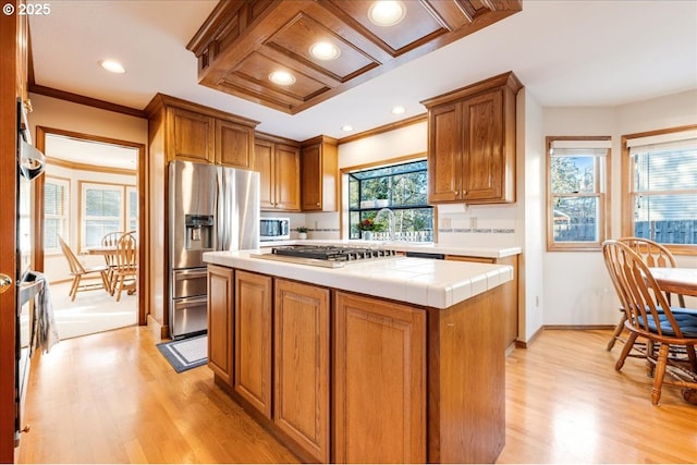 kitchen featuring a kitchen island, ornamental molding, tile countertops, and appliances with stainless steel finishes