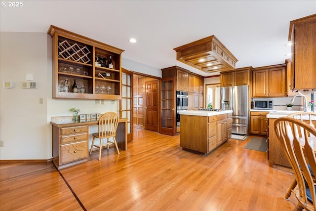 kitchen featuring stainless steel appliances, a kitchen island, sink, and light hardwood / wood-style flooring