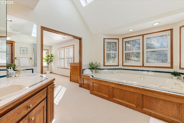 bathroom with vanity, a skylight, high vaulted ceiling, and a bathing tub