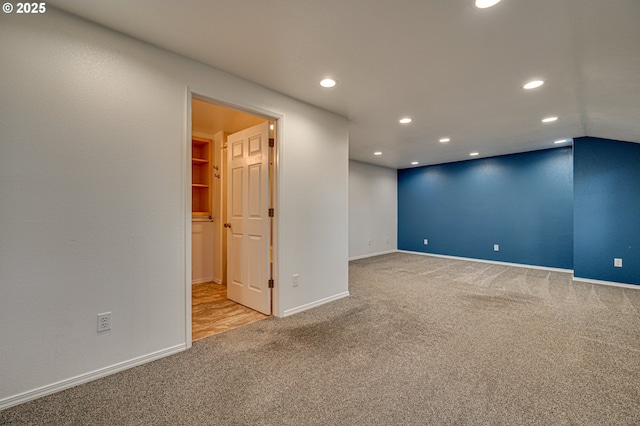 spare room with lofted ceiling, recessed lighting, light colored carpet, and baseboards