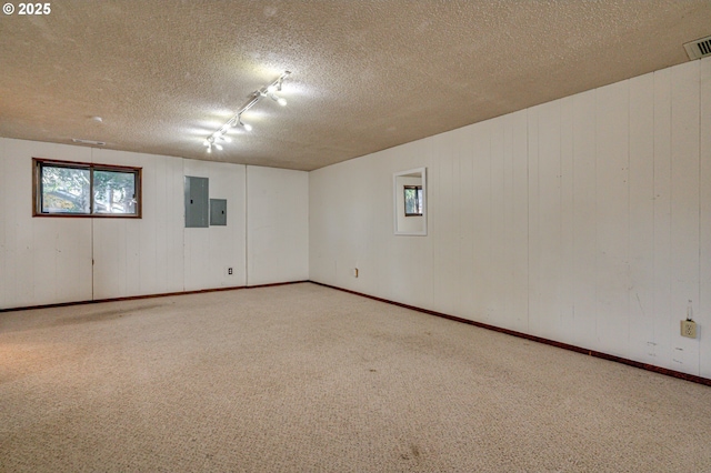 carpeted empty room with visible vents, baseboards, a textured ceiling, and electric panel