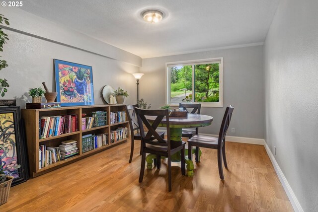 dining room with wood finished floors, a textured wall, and baseboards
