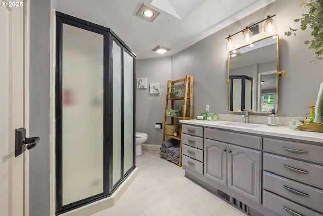 full bath with a stall shower, vanity, toilet, and a skylight