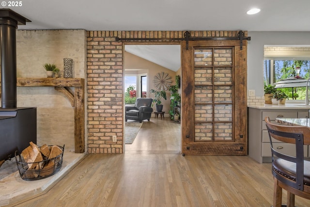 dining area with healthy amount of natural light, a barn door, wood finished floors, a wood stove, and recessed lighting