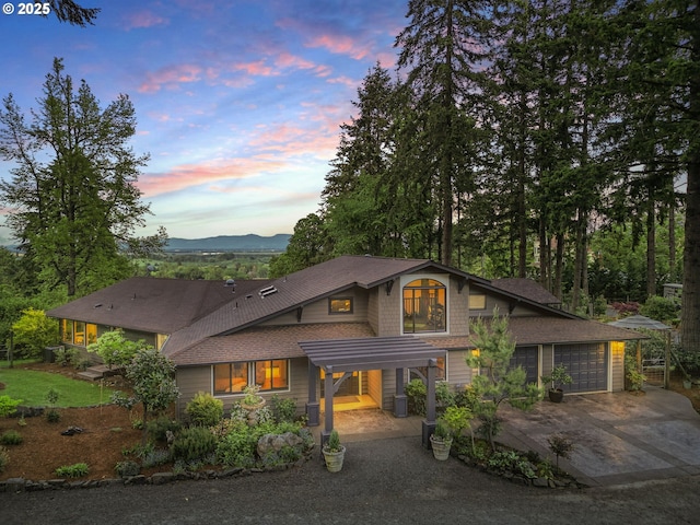 view of front of home with driveway, a garage, a shingled roof, and a mountain view
