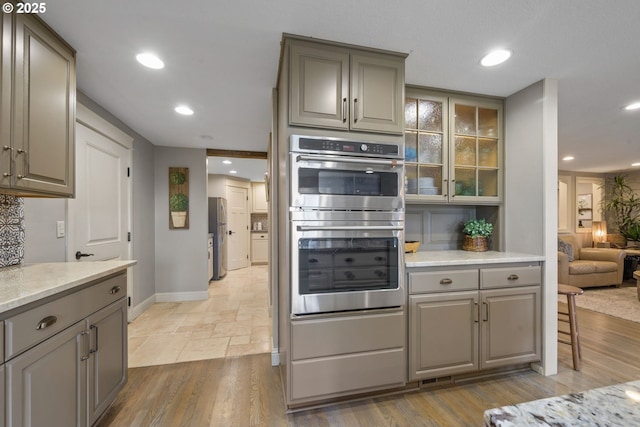 kitchen with gray cabinetry, appliances with stainless steel finishes, baseboards, glass insert cabinets, and recessed lighting
