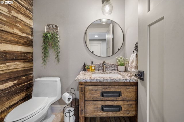 bathroom featuring toilet, vanity, and baseboards