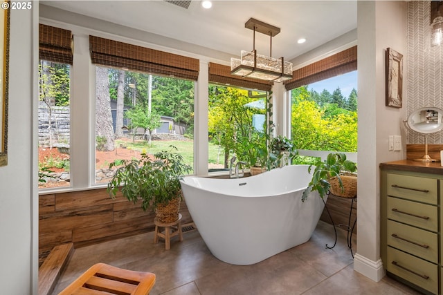 full bathroom with plenty of natural light, a freestanding bath, vanity, and recessed lighting