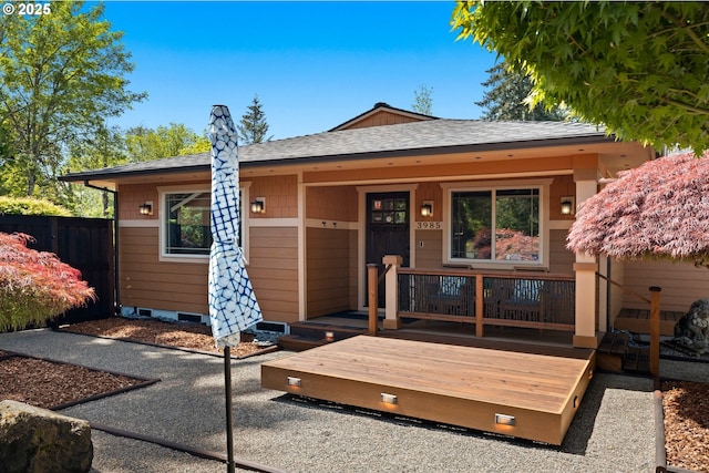 view of front facade featuring a shingled roof and fence