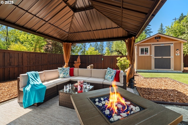 view of patio featuring a storage shed, an outdoor living space with a fire pit, an outdoor structure, a gazebo, and a fenced backyard