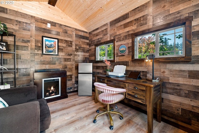 office space with light wood finished floors, wood ceiling, wooden walls, a warm lit fireplace, and lofted ceiling
