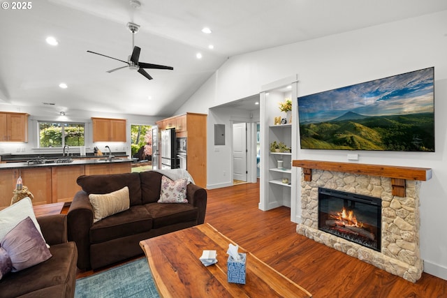 living room featuring a ceiling fan, baseboards, wood finished floors, and lofted ceiling