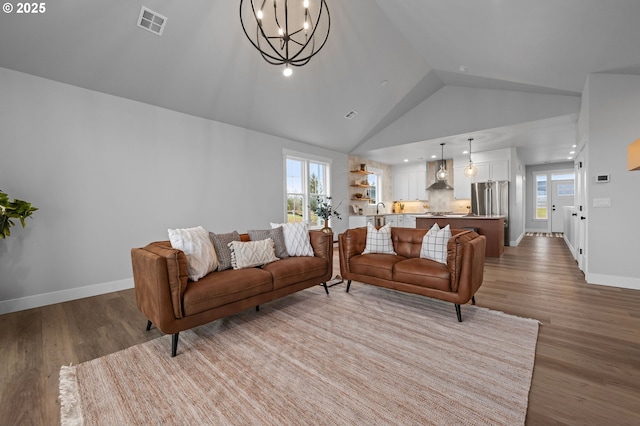 living room with light wood-type flooring, a notable chandelier, plenty of natural light, and baseboards