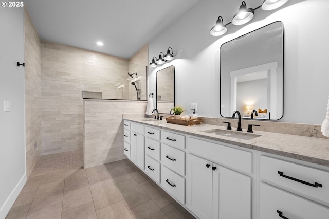 full bath featuring double vanity, a walk in shower, a sink, and tile patterned floors