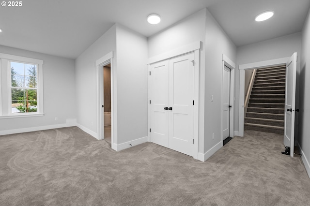 unfurnished bedroom featuring multiple closets, light colored carpet, and baseboards