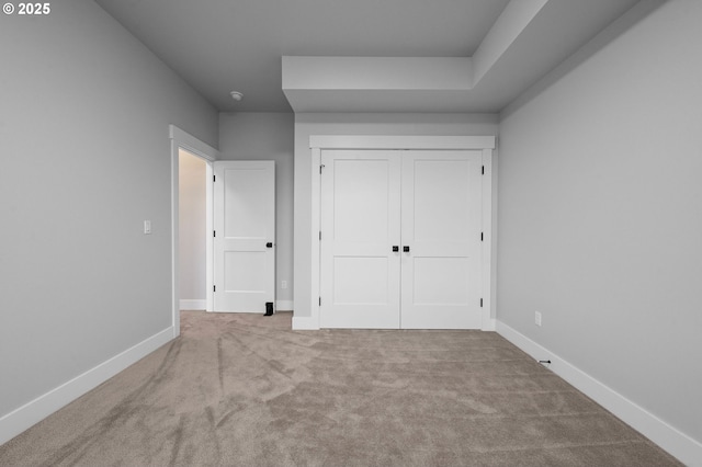 unfurnished bedroom featuring a closet, light carpet, and baseboards