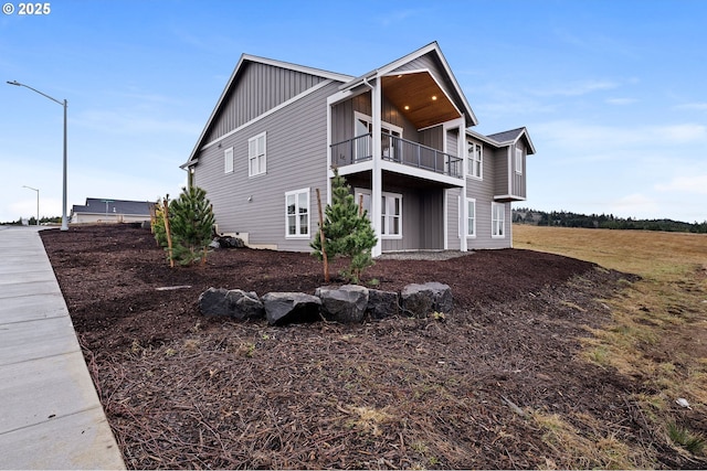 rear view of house with board and batten siding and a balcony