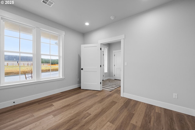 empty room with light wood finished floors, baseboards, visible vents, and recessed lighting