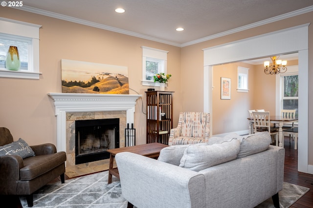 living room featuring hardwood / wood-style flooring, ornamental molding, a high end fireplace, and a notable chandelier