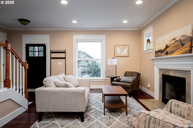 living room with crown molding, wood-type flooring, and a tile fireplace