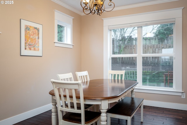 dining room featuring crown molding, a healthy amount of sunlight, dark wood-type flooring, and a notable chandelier