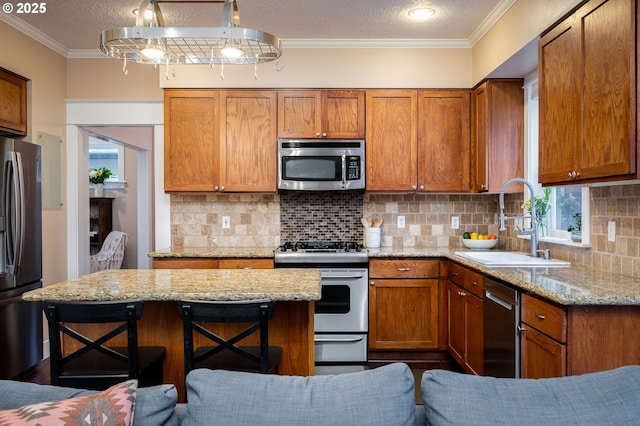 kitchen featuring sink, crown molding, a breakfast bar area, stainless steel appliances, and light stone counters