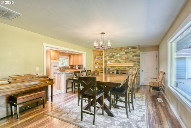 dining room featuring visible vents, baseboards, an inviting chandelier, and wood finished floors