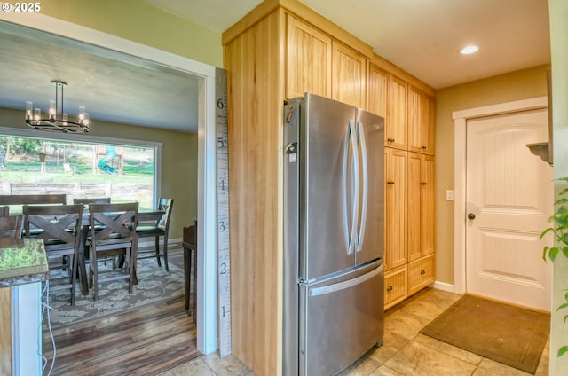 kitchen with light brown cabinets, baseboards, recessed lighting, freestanding refrigerator, and a notable chandelier