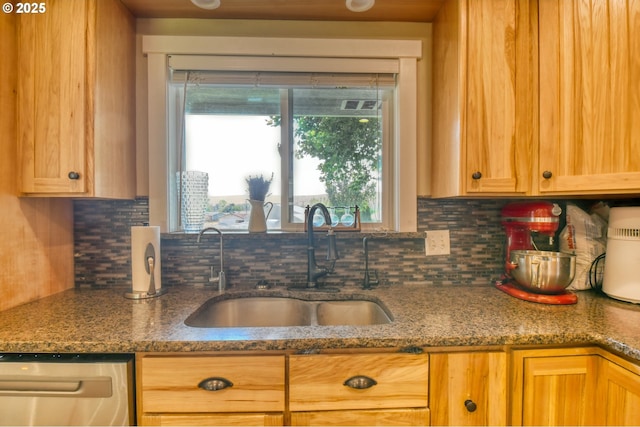 kitchen featuring a sink, decorative backsplash, dishwasher, and dark stone countertops