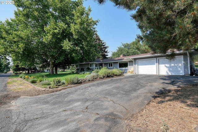 ranch-style house with aphalt driveway, a garage, and a chimney