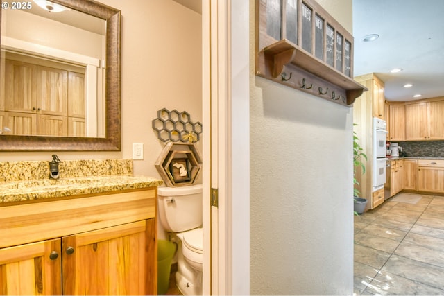 bathroom featuring vanity, toilet, recessed lighting, and backsplash