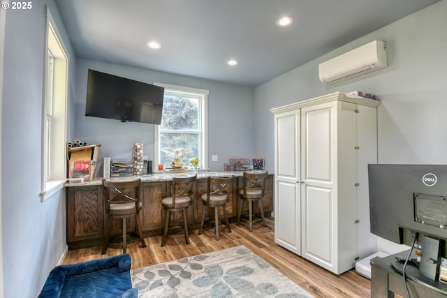 interior space featuring a wall mounted air conditioner, recessed lighting, a bar, and light wood-style floors