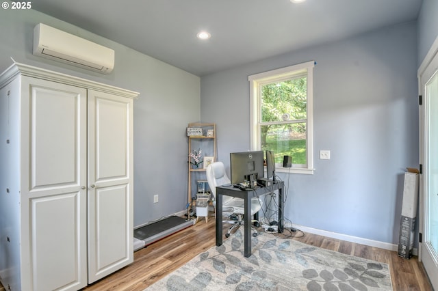 office with a wall mounted air conditioner, baseboards, and light wood finished floors