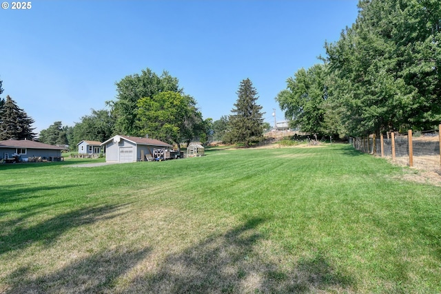 view of yard with an outdoor structure, fence, and a detached garage