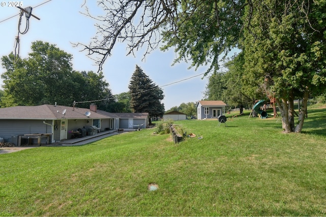 view of yard featuring a garage, an outdoor structure, and a playground