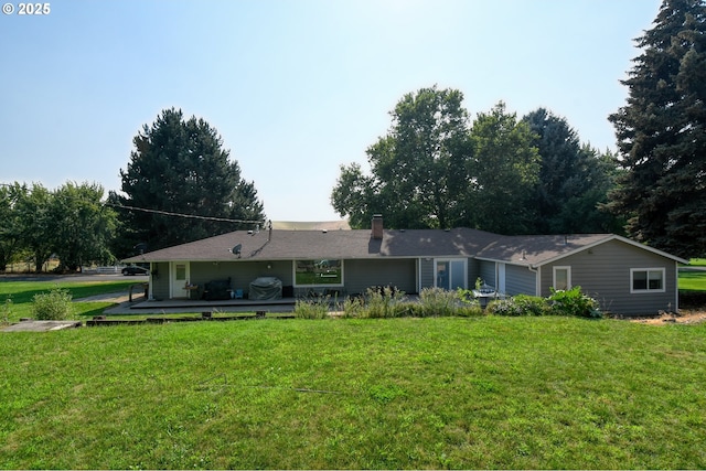 back of house with a lawn, a deck, and a chimney