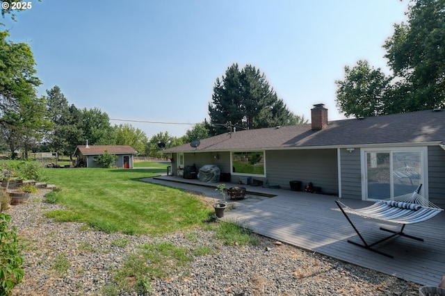 rear view of house with a yard, an outbuilding, a deck, and a chimney