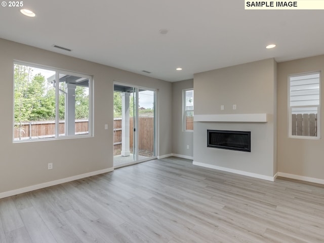732 NW 178th Way, Ridgefield, WA 98642 - unfurnished living room featuring baseboards, light wood-type flooring, recessed lighting, and a glass covered fireplace