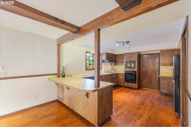 65257 E Sandy River Ln, Rhododendron, OR 97049 - kitchen featuring a peninsula, under cabinet range hood, wood finished floors, beam ceiling, and light countertops
