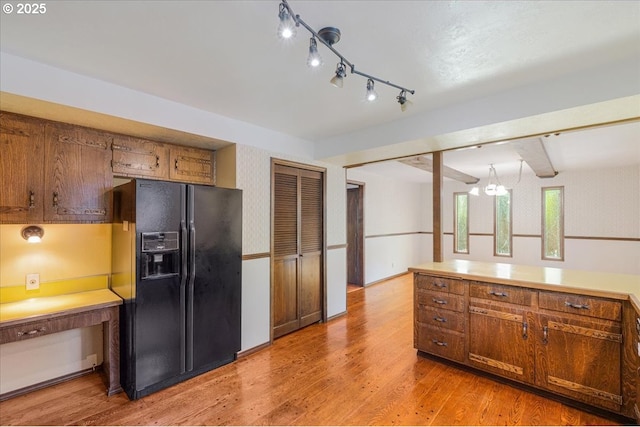 65257 E Sandy River Ln, Rhododendron, OR 97049 - kitchen with black fridge, light wood-style floors, brown cabinetry, and light countertops