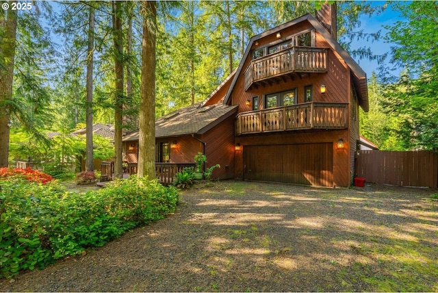 65257 E Sandy River Ln, Rhododendron, OR 97049 - back of house featuring a balcony, a garage, dirt driveway, and a chimney