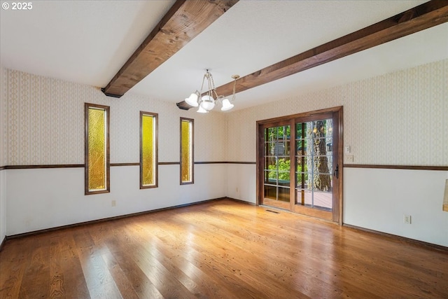 65257 E Sandy River Ln, Rhododendron, OR 97049 - unfurnished room with wallpapered walls, a chandelier, wood finished floors, beamed ceiling, and baseboards