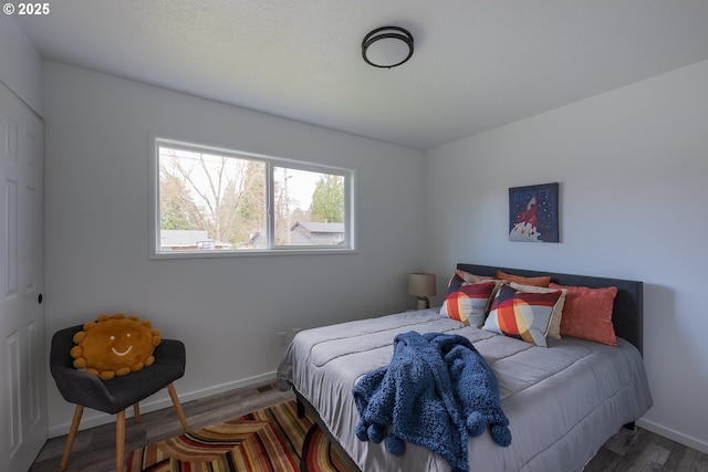 bedroom with baseboards and wood finished floors